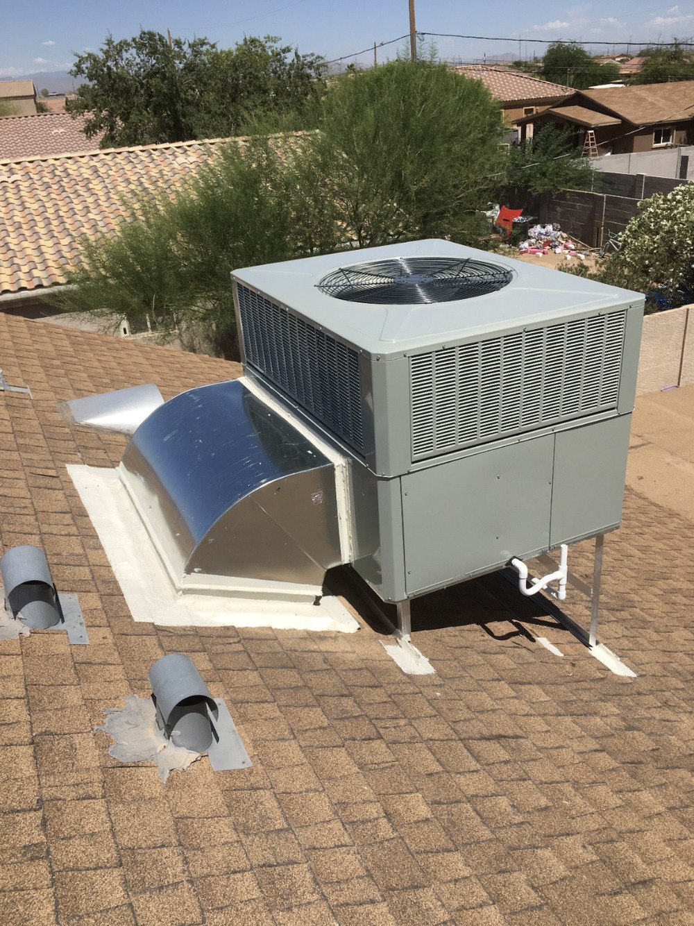 Close view of a rooftop AC unit's fan housing and refrigerant lines during service