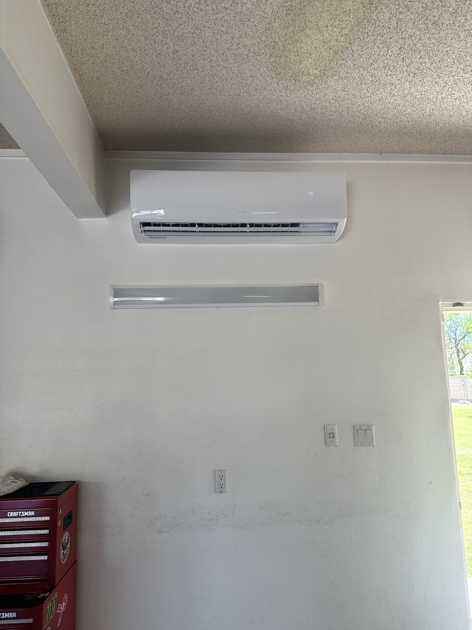 Indoor wall-mounted mini split unit installed above a garage workspace
